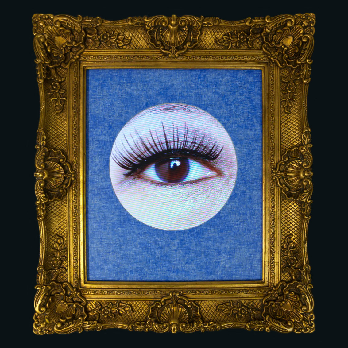 A circular cut out photo of a human eye with long lashes framed in an ornate gold-coloured picture frame.